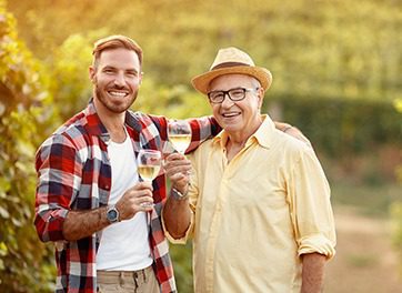 Father and Son smiling while toasting white wine glasses in a Vineyard