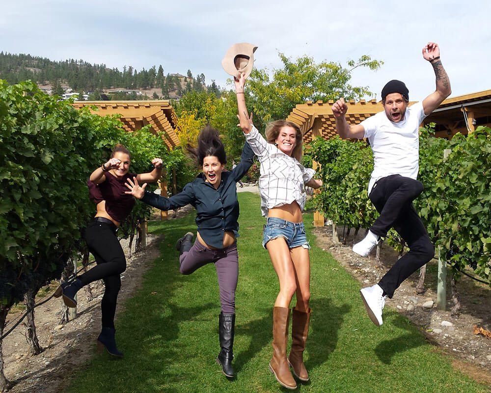 Four Friends jumping in a vineyard on a Cheers Okanagan Wine Tour in Summerland